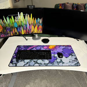 colorful neoprene desk mat on a white desk with a keyboard and mouse